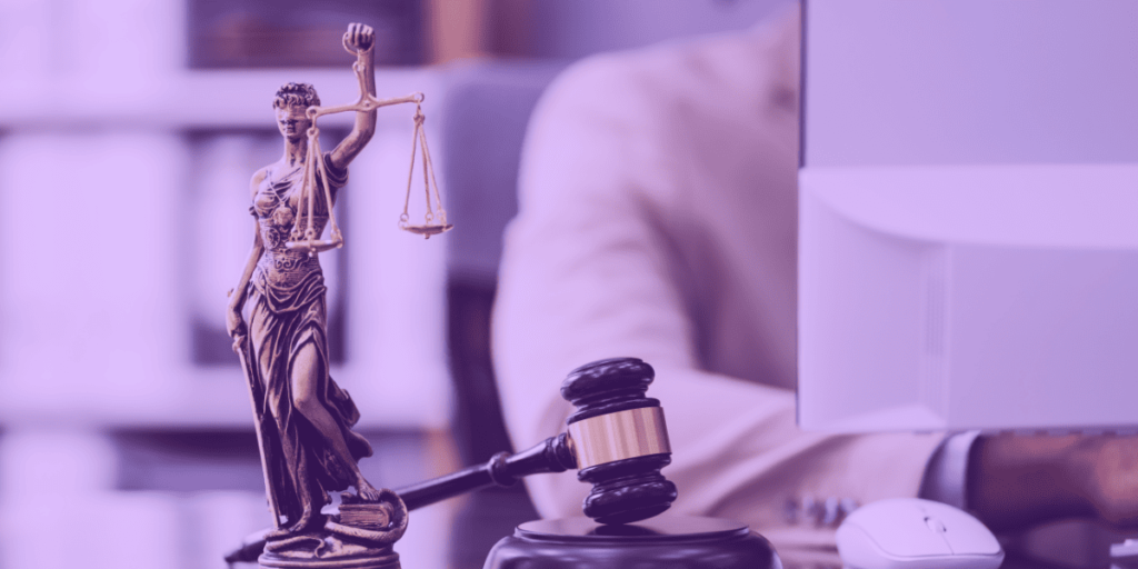 A estátua da Justiça, o martelo e um advogado trabalhando no computador.