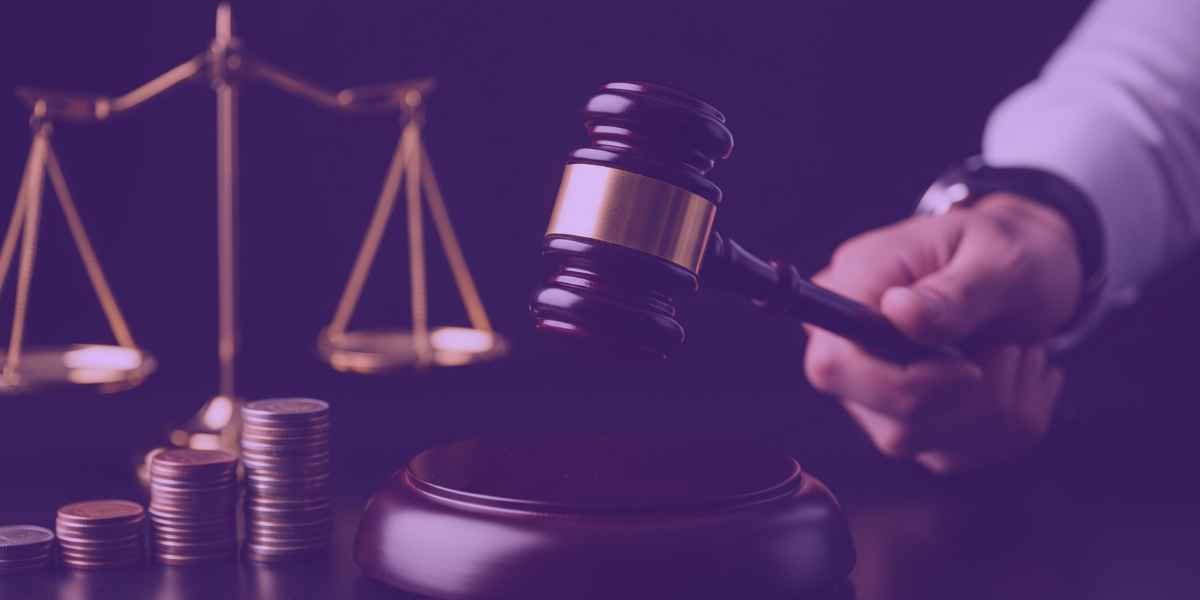 A imagem mostra uma balança da justiça ao lado de pilhas de moedas e um martelo de juiz sendo segurado,