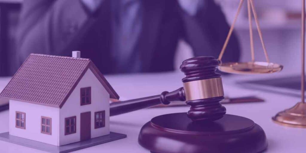 Um advogado escrevendo uma ação de usucapião, ao lado, um martelo da justiça, uma miniatura de uma casa.