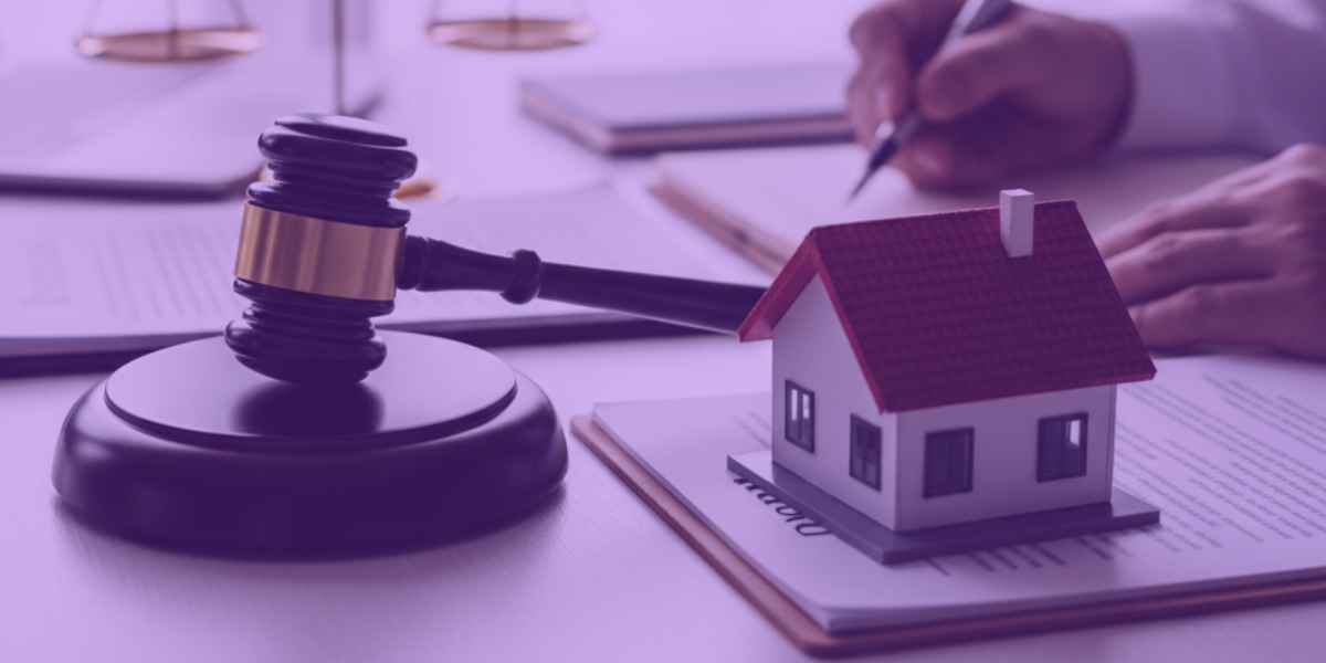 Um advogado escrevendo uma ação de usucapião, ao lado, um martelo da justiça, uma miniatura de uma casa e a balança representando a justiça.
